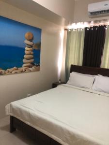 a bedroom with a bed and a painting of a stack of rocks at Holiday Suite One Bedroom Condo Unit in Iloilo City +16 photos
