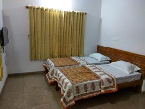 two twin beds in a room with a window at Aashraya Home Stay in Mysore +5 photos