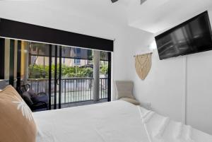 une chambre avec un lit blanc et une télévision à écran plat dans l'établissement Macrossan Magic - A Boutique Tropical Resort, à Port Douglas 34 autres photos