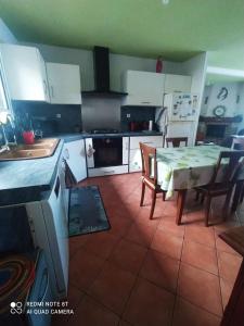 una cucina con tavolo, sedie e armadietti bianchi di Ti'Commerson a Maison de lʼEnfance