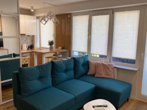 a living room with a blue couch and a kitchen at DiM Suwałki Pułaskiego in Suwałki
