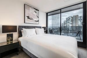 a bedroom with a white bed and a large window at Sunlit & Sleek Condo in Lively St Kilda in Melbourne