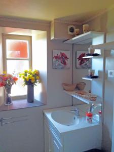 ein Badezimmer mit Waschbecken und einem Fenster mit Blumen in der Unterkunft La calade de Joux in Chassiers