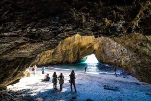 un gruppo di persone in piedi su una spiaggia vicino a una grotta di Izu One Club - Vacation STAY 10342v a Futo