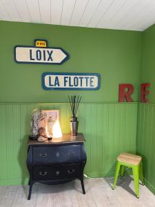 a room with a green wall with a dresser and a sign at Le Petit Bois in Sainte-Marie-de-Ré