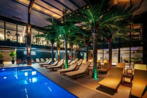 a hotel pool with chairs and palm trees at Hotel Nordic Twins & Wellness in Rădăuţi