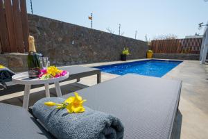a patio with a table and a bottle of wine and flowers at Villa SERENITY neuve,4 chambres, 5 min de la plage in Calodyne