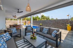 a patio with couches and a table and a pool at Villa SERENITY neuve,4 chambres, 5 min de la plage in Calodyne