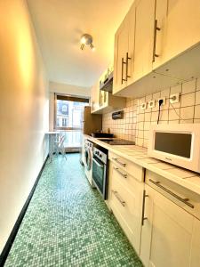Una cocina con gabinetes blancos y piso verde. en Champs elysees apartment 4, en París