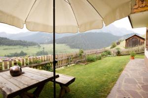 een houten bank met een paraplu in het gras bij Haus Prieth in Nauders