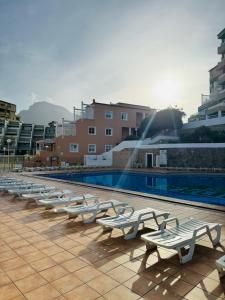 a row of white benches sitting next to a swimming pool at Costa Adeje Orlando Tenerife Sea View - Pool - AC in Adeje