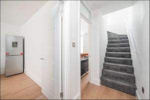 a staircase in a white room with a gray carpet at COSY Modern HOME Euston Fitzrovia in London