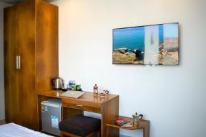 a room with a desk with a laptop on a wall at Trang Ngan Hotel by THG in Danang