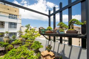 a balcony with bonsai trees on a building at Trang Ngan Hotel by THG in Danang