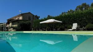 una gran piscina con sombrilla y sillas en Villa Cristina modern farmhouse with Private Pool, en Monsagrati