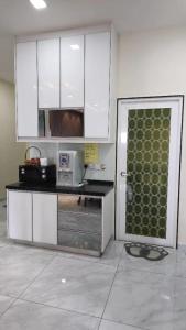 a kitchen with white cabinets and a door with a microwave at Countryside Penthouse @ One Residence Sekinchan in Sekincan