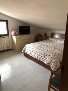 a bedroom with a bed and a dresser with a television at Il nido dell amore in Albiano