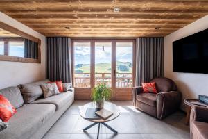 オトリュスにあるAppartements Les Saisies Hautlieuxのソファと椅子、大きな窓のあるリビングルーム