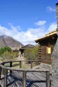 eine Holzterrasse vor einer Blockhütte in der Unterkunft Pueblo Del Rio Mountain Lodge & Spa in Potrerillos