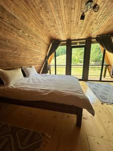a bed in a room with a large window at Cabana Piatra Codrilor in Sunători