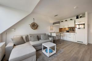 Una sala de estar con un sofá y una cocina. en Wohnanlage Am Mühlenteich, en Timmendorfer Strand
