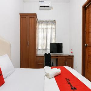 a bedroom with two beds and a desk with a television at RedDoorz near Trans Studio Mall Cibubur in Depok
