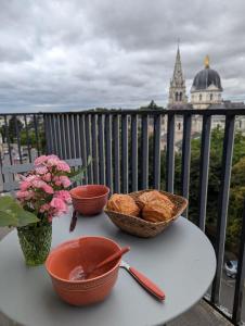 een tafel met kommen met eten en bloemen op een balkon bij Sylonie in Châteauroux +2 foto's