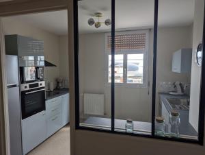 een keuken met witte apparatuur en een groot raam bij Sylonie in Châteauroux