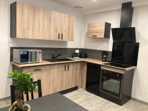 a kitchen with black appliances and wooden cabinets at Maisonnette in Magny-Jobert