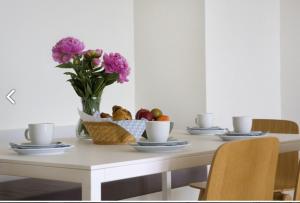a table with a vase of flowers and a basket of fruit at Osean by BLOSS luxe appartement met frontaal zeezicht, binnenzwembad en parking in Middelkerke