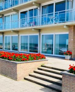 a building with a staircase and flowers in front of it at Osean by BLOSS luxe appartement met frontaal zeezicht, binnenzwembad en parking in Middelkerke