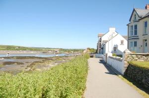 Un camino al lado de una playa con casas y el océano. en Y Cwtch Newport Pembrokeshire, en Newport