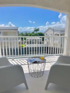 a balcony with two chairs and a table on a porch at Villa - Cosy - Piscine - Guadeloupe centre in Baie-Mahault +6 photos