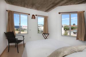a bedroom with a bed and a chair and windows at Complejo Aguazul in La Pedrera