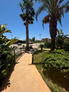 a sidewalk with two palm trees and a fence at Casa Golf Mar Menor in Los Martínez