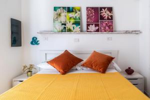 a bedroom with a yellow bed with orange pillows at Green Emerald by BarbarHouse in Polignano a Mare