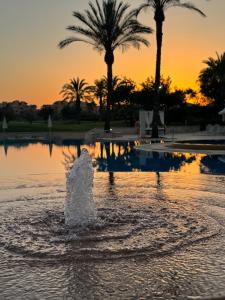 a fountain in the water with a sunset in the background at Casa Golf Mar Menor in Los Martínez