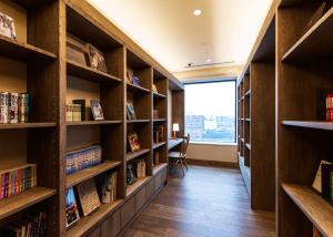 una biblioteca con estanterías de madera y libros en JR Inn Asahikawa, en Asahikawa