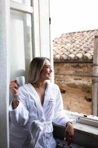 une femme assise sur le rebord d'une fenêtre tenant une tasse de café dans l'établissement Raffaello - M&M Holiday House, à Pérouse 41 autres photos