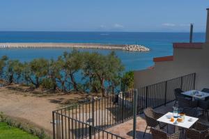 a balcony with a table and chairs and the ocean at Villa Vincenza Deluxe Rooms in Capo dʼOrlando