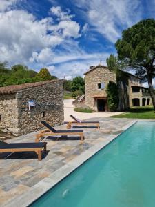una piscina di fronte a un edificio in pietra con lettini di Mas de Rofa proche Pôle mécanique Alès a Saint-Martin-de-Valgalgues
