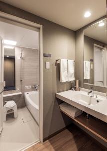 a bathroom with a sink and a tub and a toilet at JR Inn Asahikawa in Asahikawa