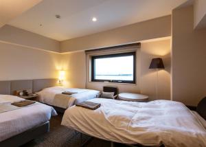 a hotel room with two beds and a window at JR Inn Asahikawa in Asahikawa