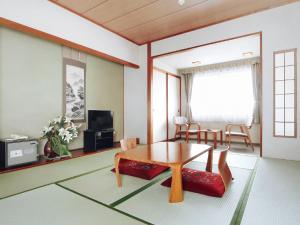 a living room with a table and a dining room at Yunokawa Kanko Hotel Shoen in Hakodate