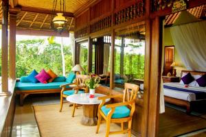 a living room with a couch and a table and chairs at Kavita 1 BR Grand Deluxe Valley View ZN236 in Ubud