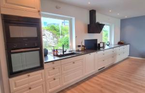 a kitchen with white cabinets and a large window at Villa with a view in Ålesund