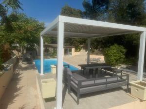 un pabellón con mesa y bancos junto a una piscina en La bergerie Emma, en Éoures