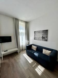 salon z niebieską kanapą i telewizorem w obiekcie Alveo Suites w Pradze