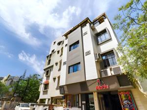 拉杰果德Hotel Atithi - Oposite Shreeji Hospital的一座高大的白色建筑,前面有汽车停放