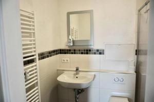 un bagno bianco con lavandino e specchio di Großzügige Monteurwohnung mit TOP Anbindung a Bensheim